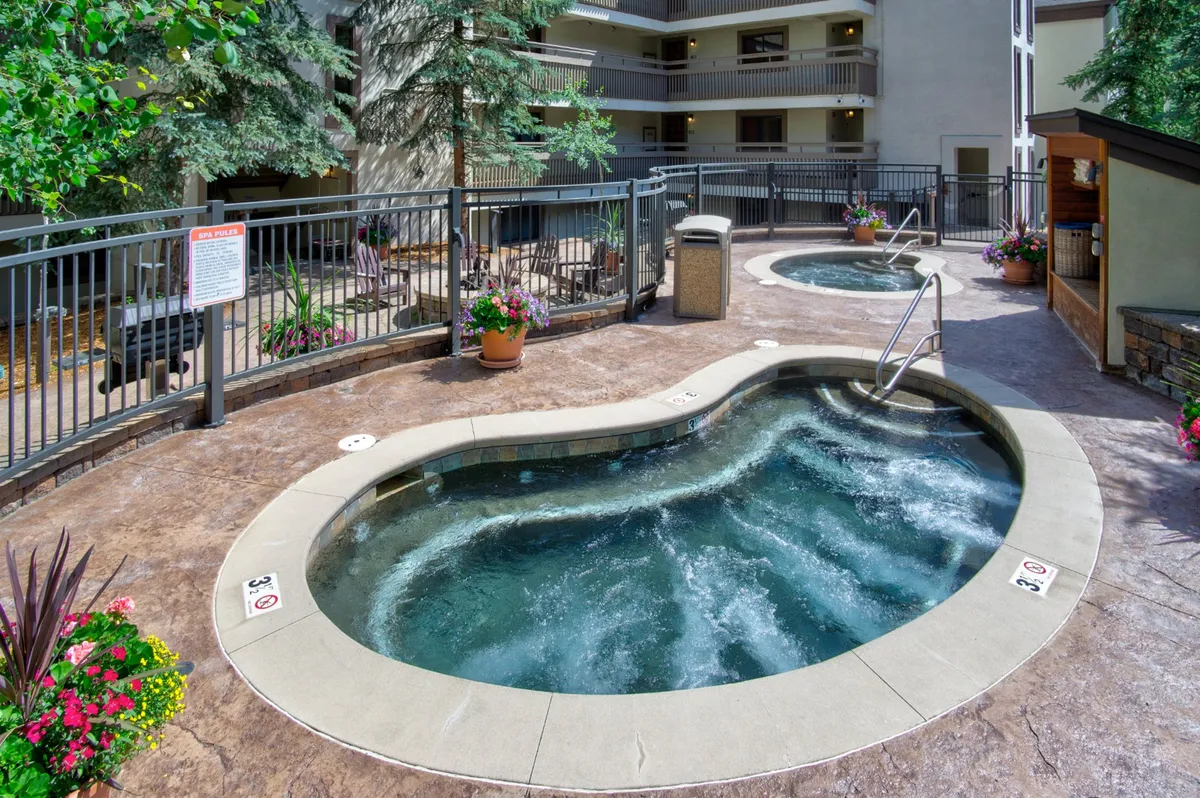 This exterior image displays inviting hot tubs surrounded by lush greenery and colorful flower pots—an ideal spot for relaxing after a day on the trails. The tranquil ambiance and outdoor setting add a sense of resort-style comfort.